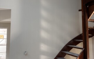 Hoge wand naast een trap professioneel afgewerkt met latex spuitwerk.